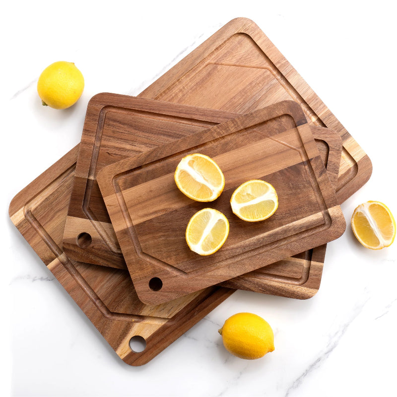 Set of 3 acacia wooden cutting boards with lemons on a white marble surface