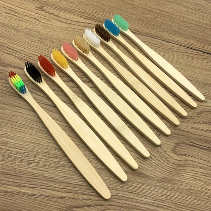 Set of bamboo toothbrushes with colored bristles on a wooden surface
