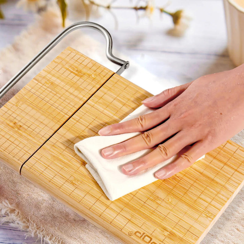 Person cleaning the Premium bamboo cheese slicer with integrated stainless steel blade
