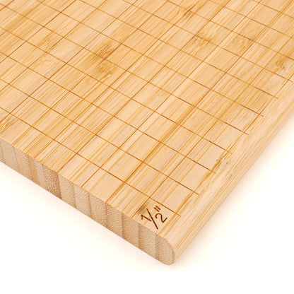 Bamboo cheese cutting board with grid pattern and measurement marking on a white background