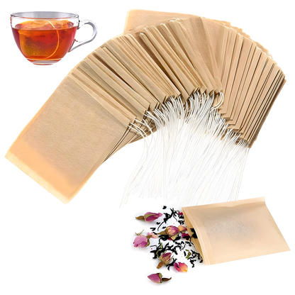 Multiple biodegradable drawstring tea bags fanned out beside a cup of brewed tea, with one bag spilling loose tea leaves and dried rose buds, shown on a white background