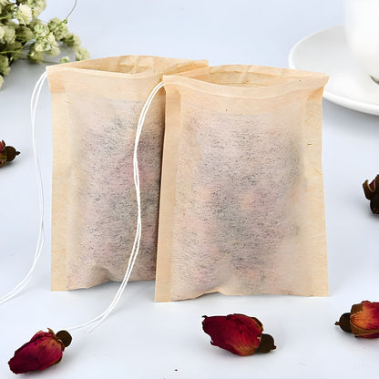 Biodegradable tea bag beside a glass cup of rose petal tea, with dried rose buds and rustic wooden details in the background.