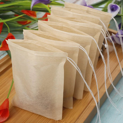 Six natural eco friendly tea bags standing in a row on a wooden tray with flowers in the background