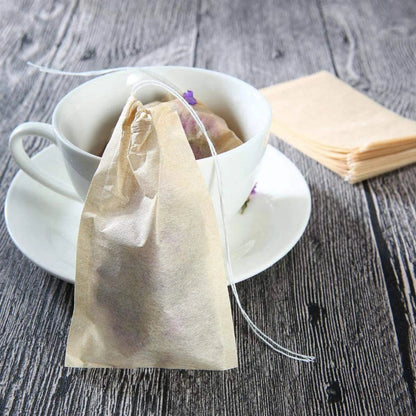 Tea bag hanging over a cup of tea on a wooden surface with napkins.