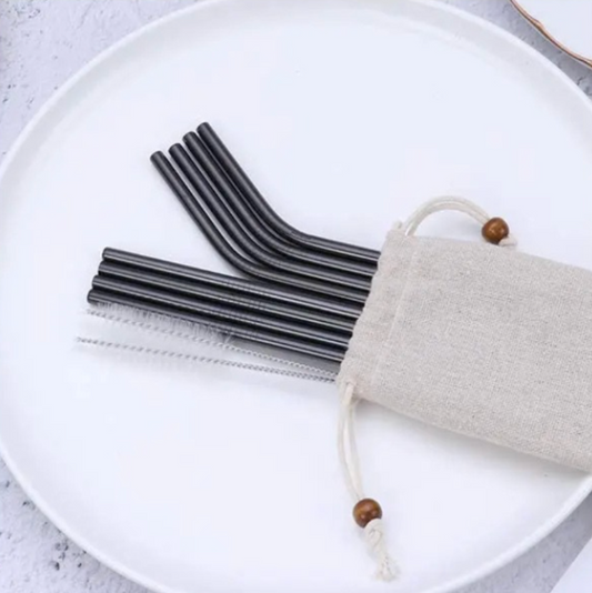 Set of black metal straws with a drawstring bag on a white plate.