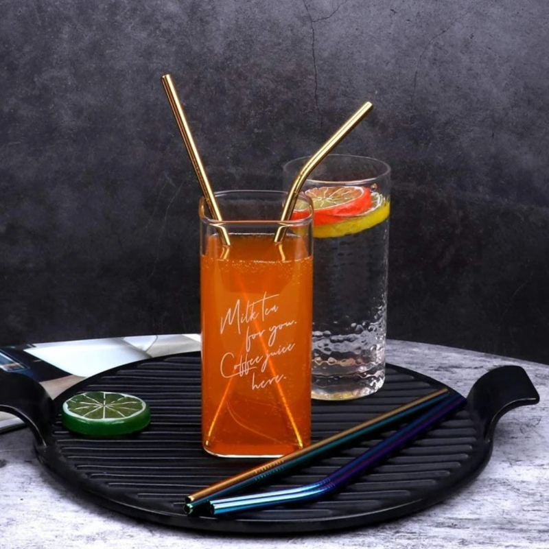Two glasses of iced tea with lemon slices and gold straws on a black tray.