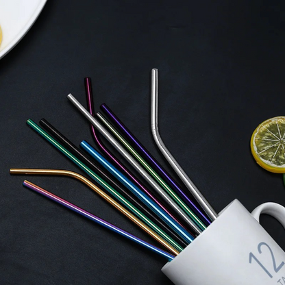 Set of colorful metal straws on a dark surface with a white mug and lemon slice.
