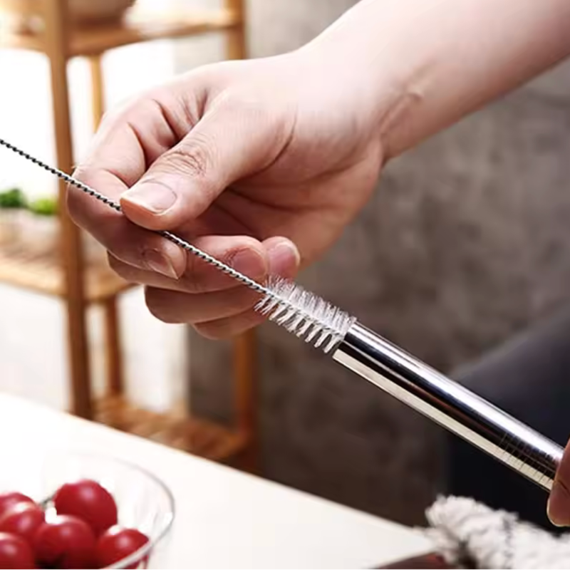 Hand holding a metal straw with a blurred background