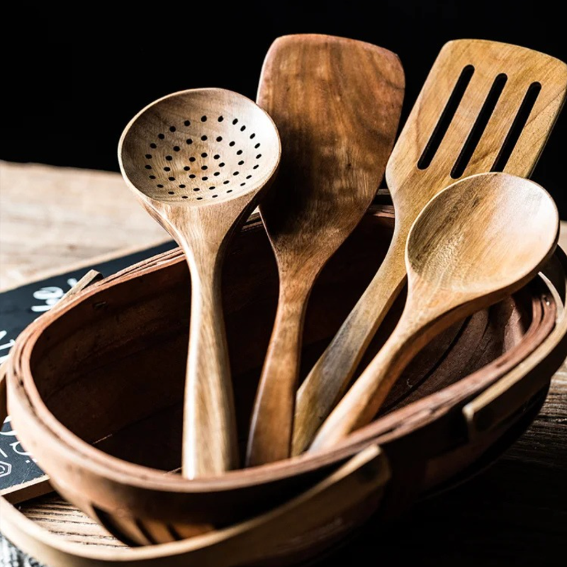 Set of wooden kitchen utensils including a ladle, spatulas, and spoons in a woven basket.
