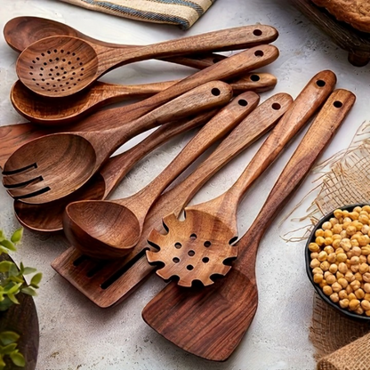 Set of wooden cooking utensils on a light surface with a bowl of beans.