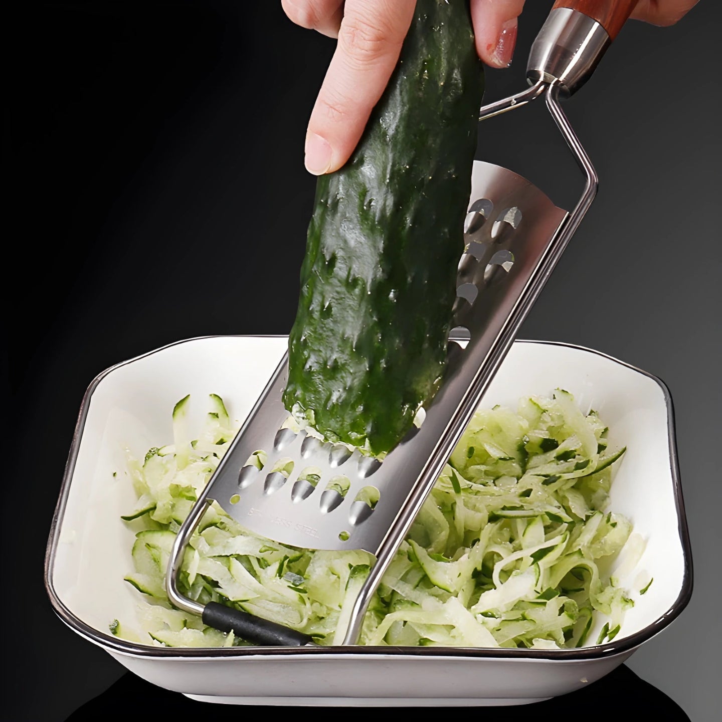Hand using a rosewood handle grater to shred cucumber into a bowl
