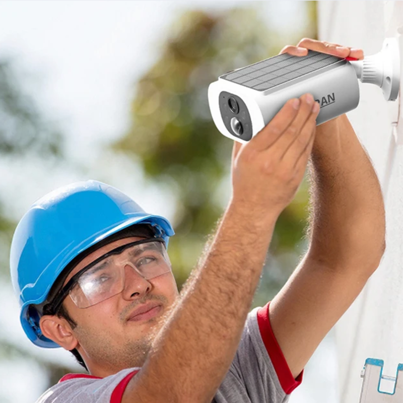 Person installing a security camera with a blurred outdoor background